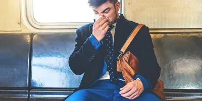 Pukumies istuu junassa ja niistää nenäänsä