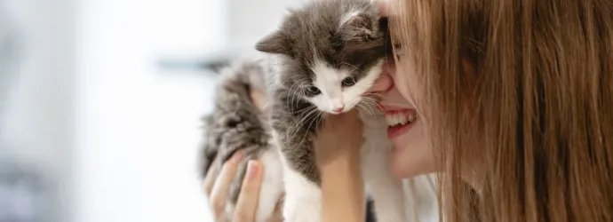 Jeune fille tenant un chaton près de son visage en souriant